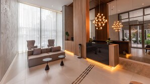 Een moderne lobby met een bank, stoelen, een receptiebalie en een bijzondere kroonluchter.