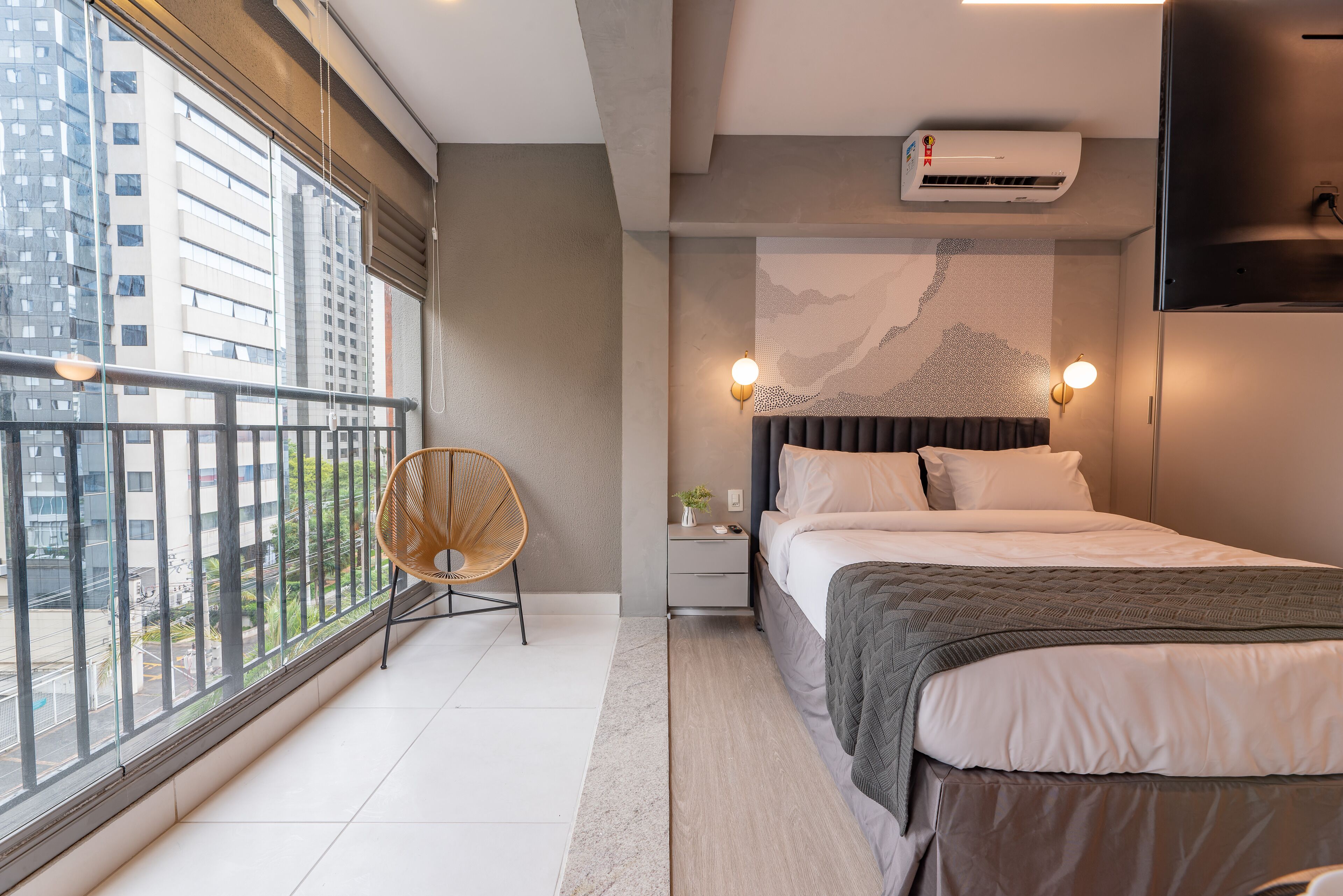 Ein modernes Schlafzimmer mit großem Fenster, einem Bett, einem Nachttisch und einem Sessel.