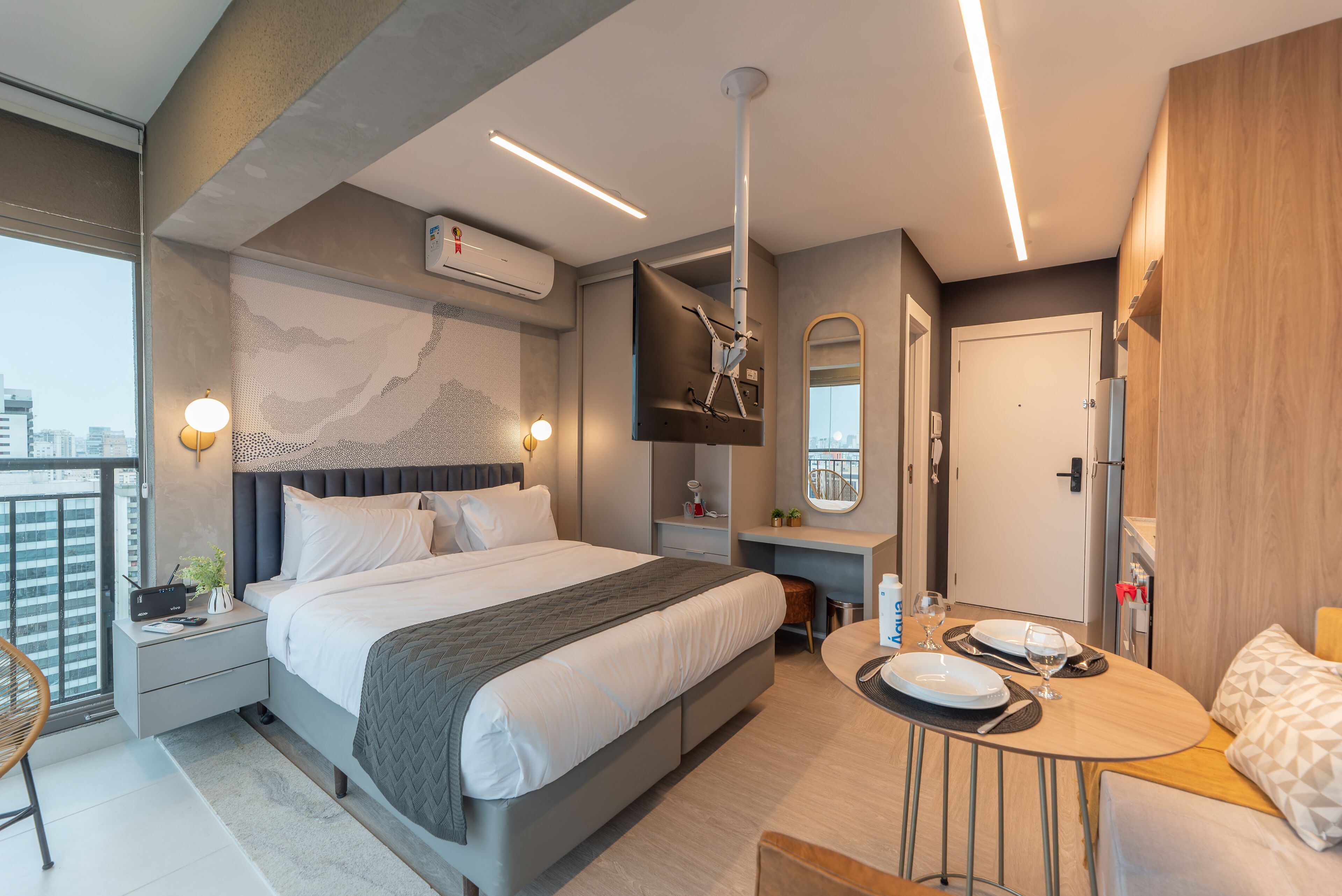 Una habitación de hotel moderna con una cama grande, mesitas de noche, un escritorio y un área de comedor.