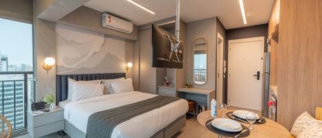 Una habitación de hotel moderna con una cama grande, mesitas de noche, un escritorio y un área de comedor.