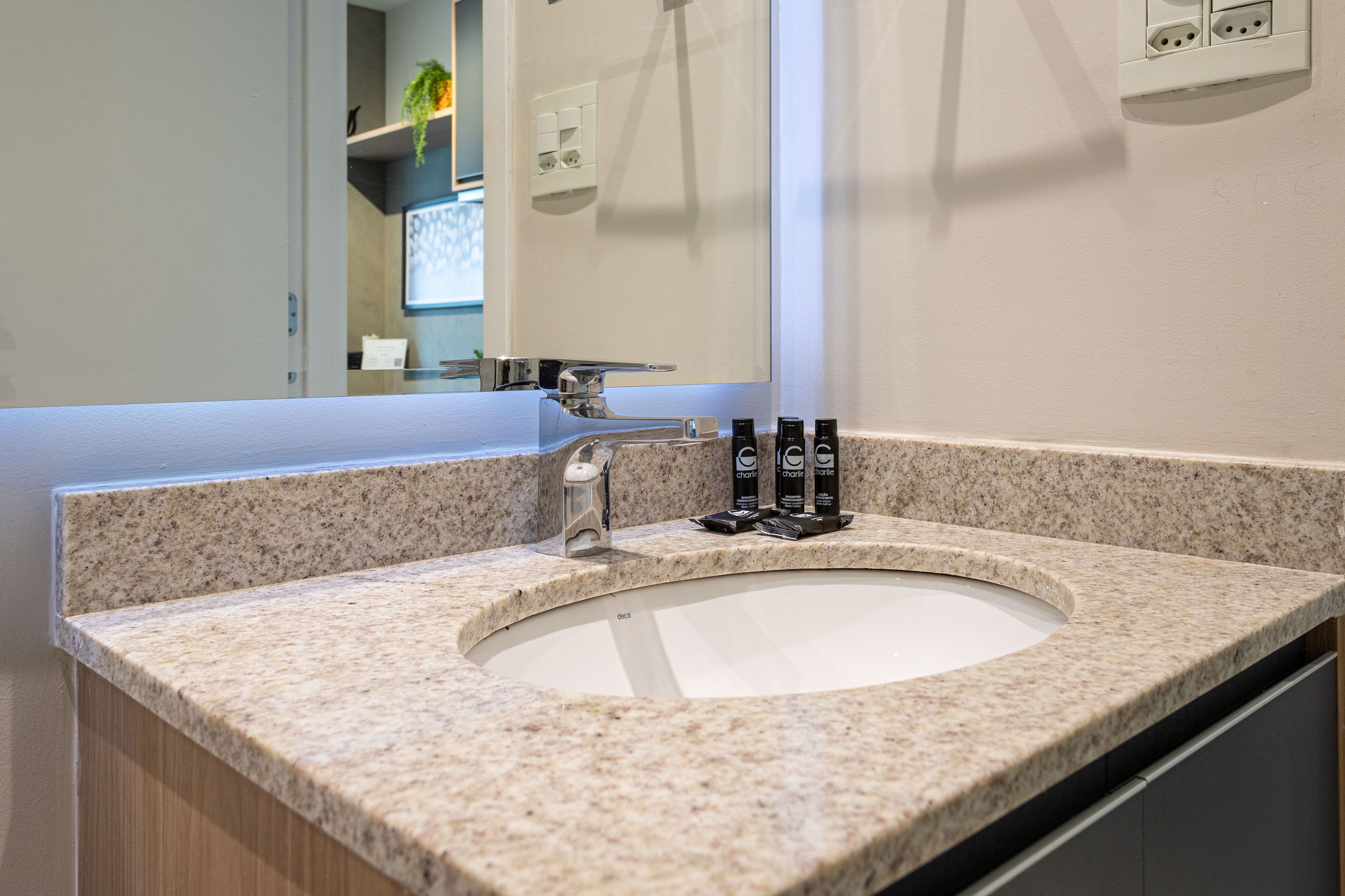 Un baño con encimera de granito, un lavabo, un espejo y un perchero para toallas.