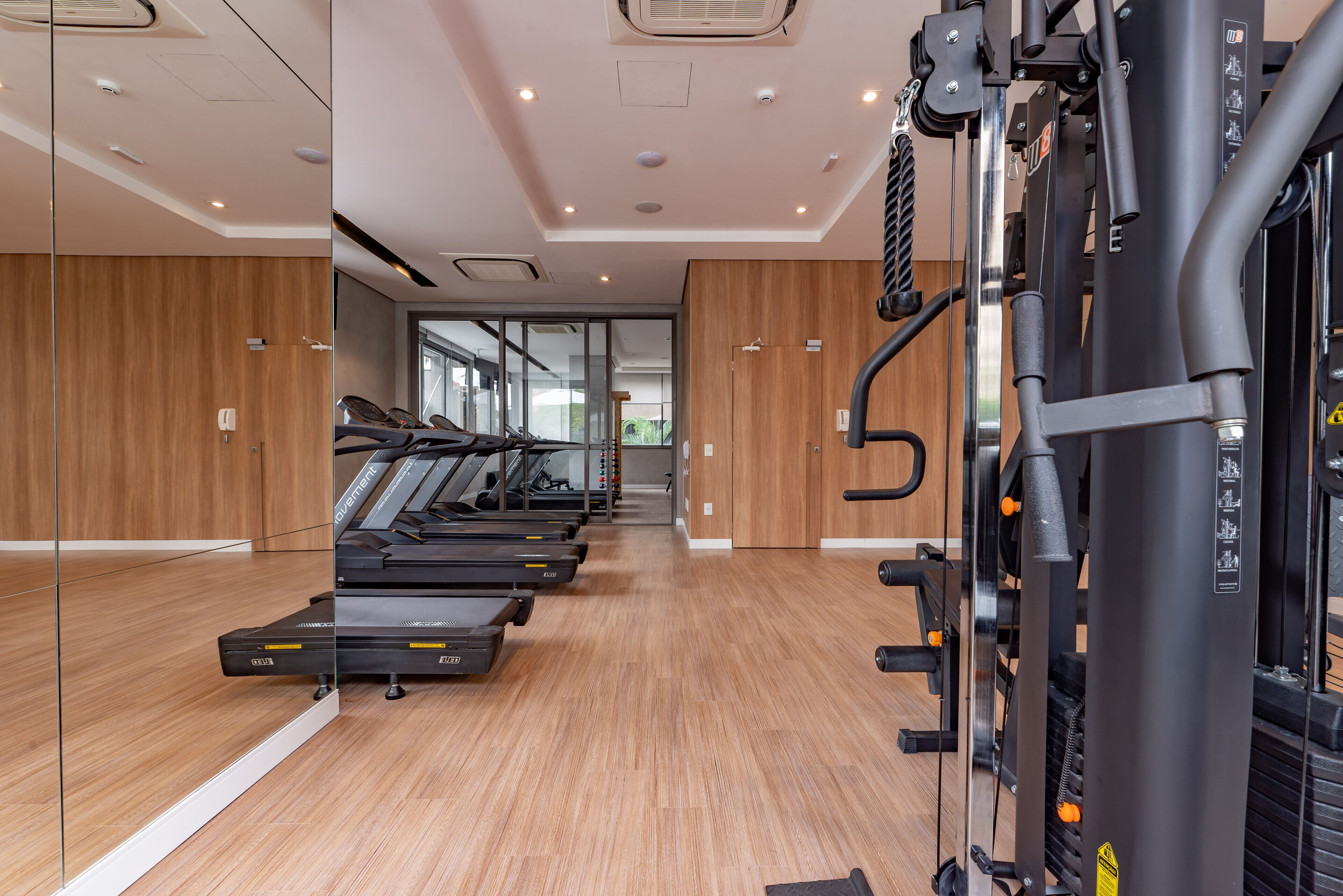 Un gimnasio con cintas de correr, máquinas de pesas y un espejo grande.