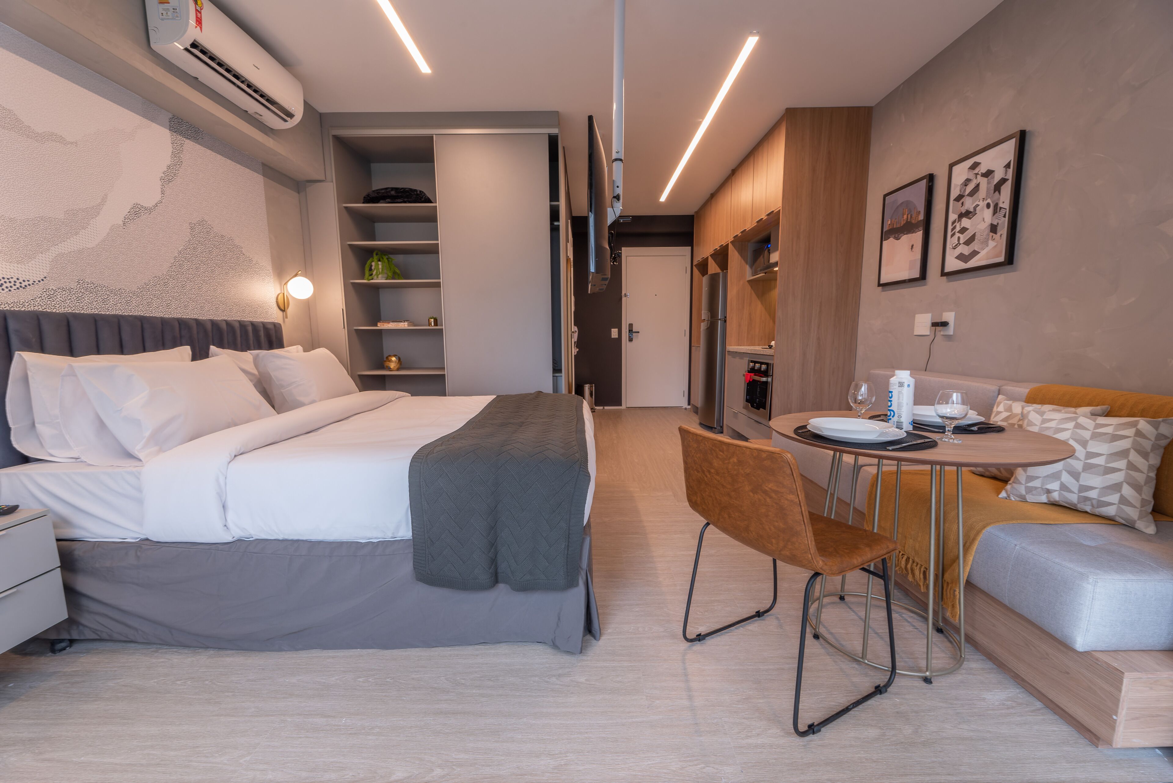 A modern hotel room with a bed, bedside table, and a small dining area with a table and chairs.