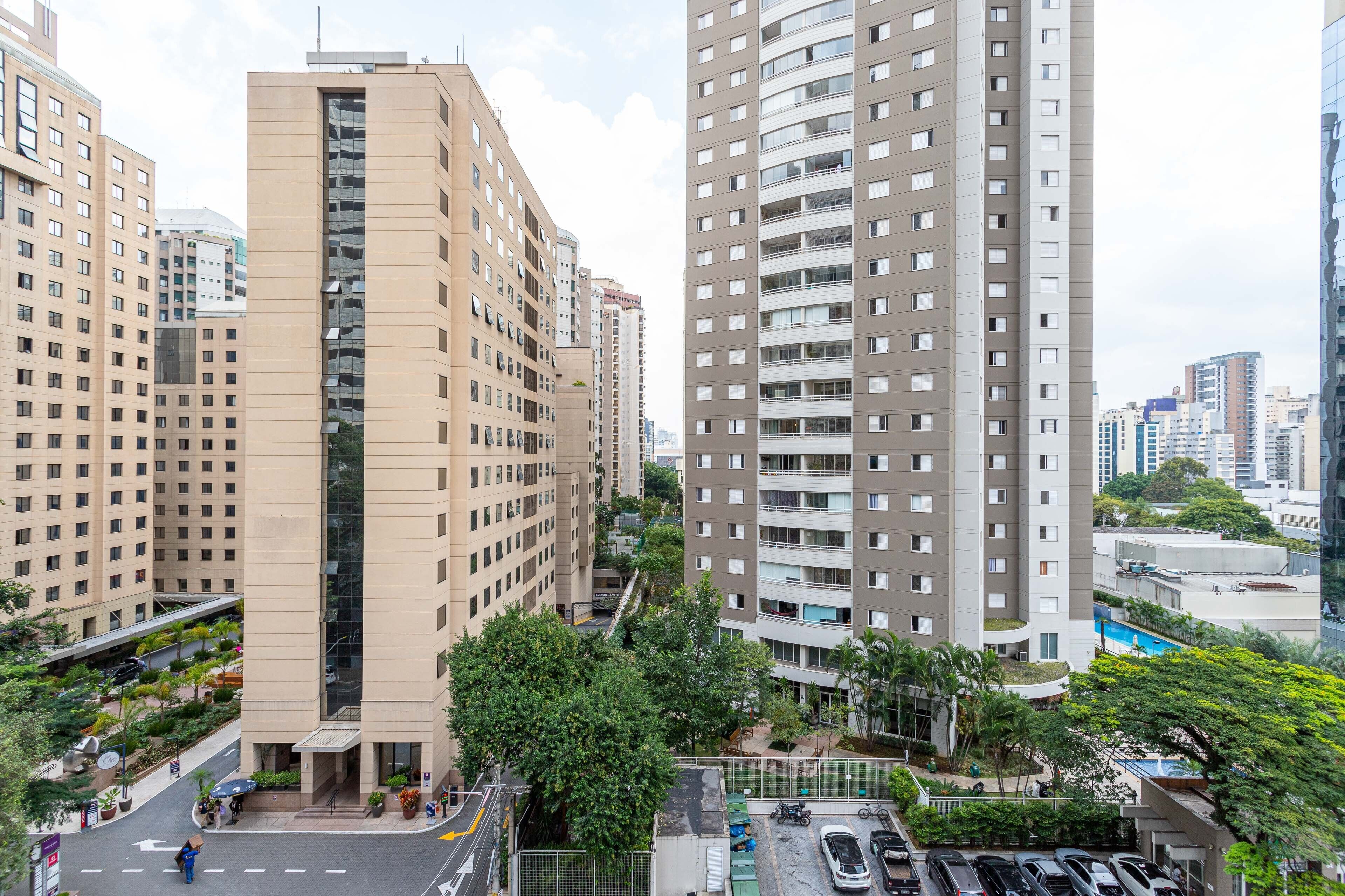 Un edificio de gran altura con varios pisos, entrada central y zonas verdes circundantes.