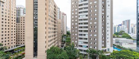 Un edificio de gran altura con varios pisos, entrada central y zonas verdes circundantes.