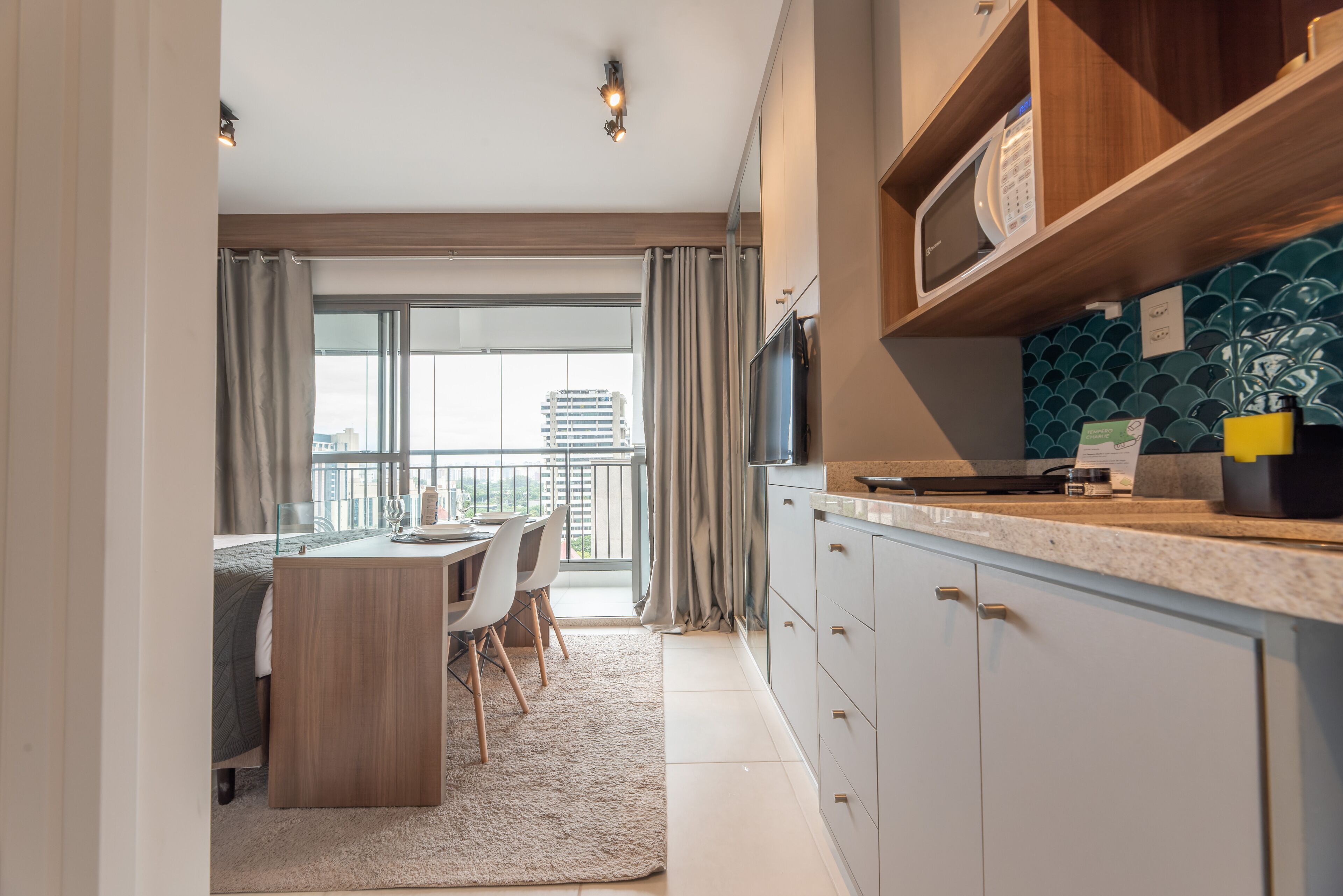 Eine moderne Küche mit integriertem Mikrowellenofen, einem Essbereich mit Tisch und Stühlen und Blick auf die Stadt durch große Fenster.