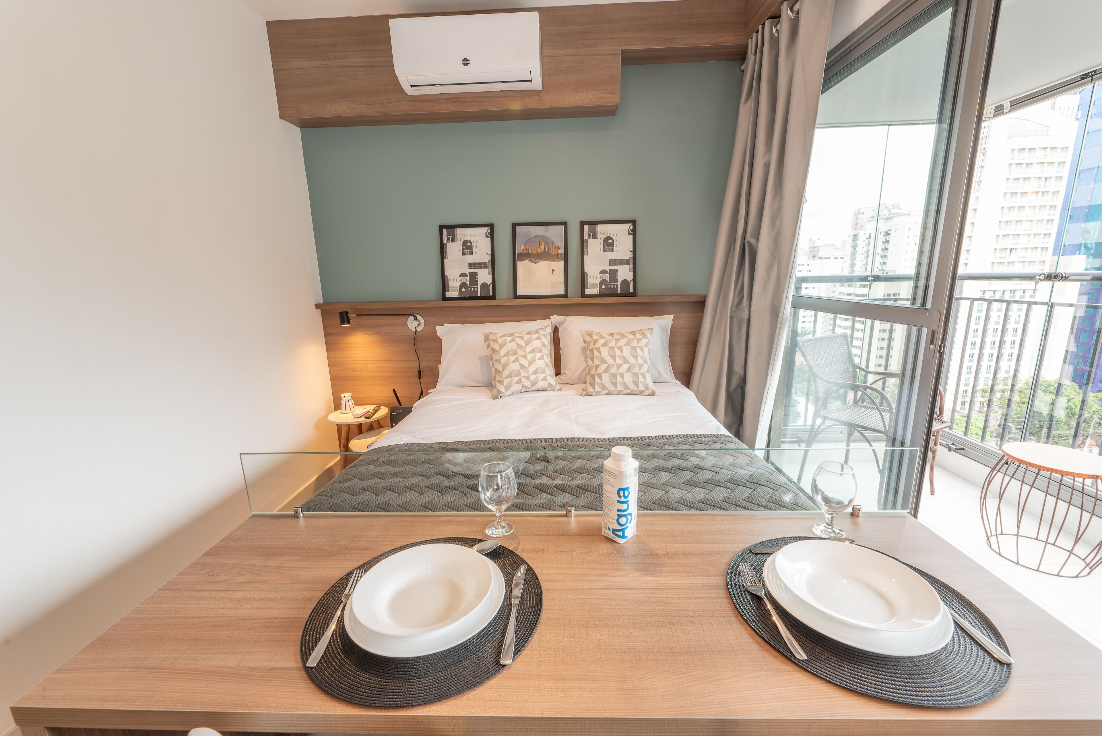 A hotel room with a bed, bedside table, and a dining table set for two.