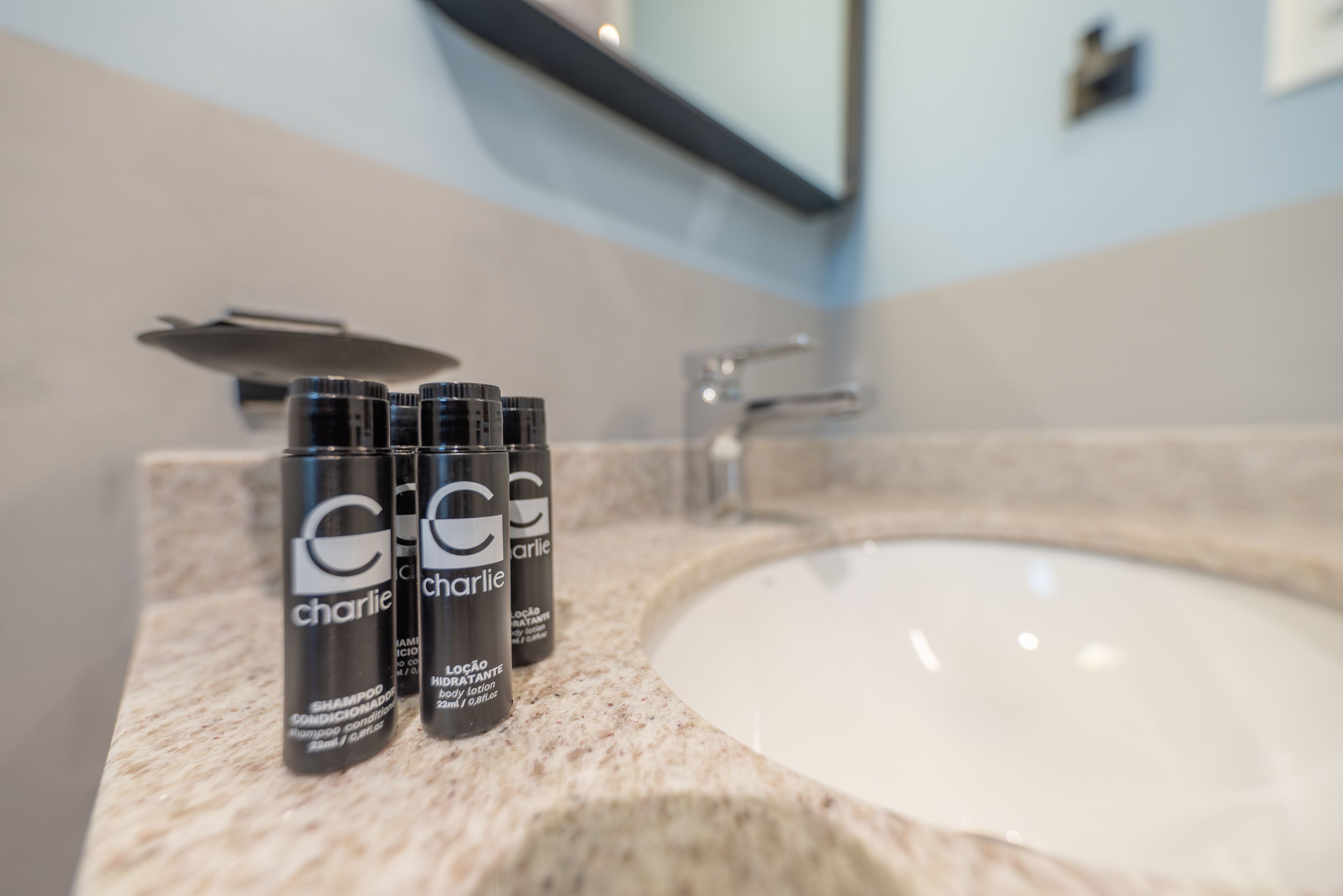 Ein Badezimmer mit einem Waschbecken und drei Flaschen Charlie Body Lotion.