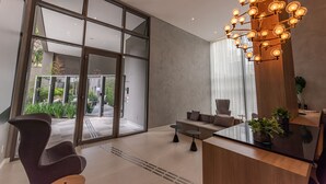 Een moderne lobby met een glazen deur, een bank, een bijzettafeltje en een decoratieve lamp.