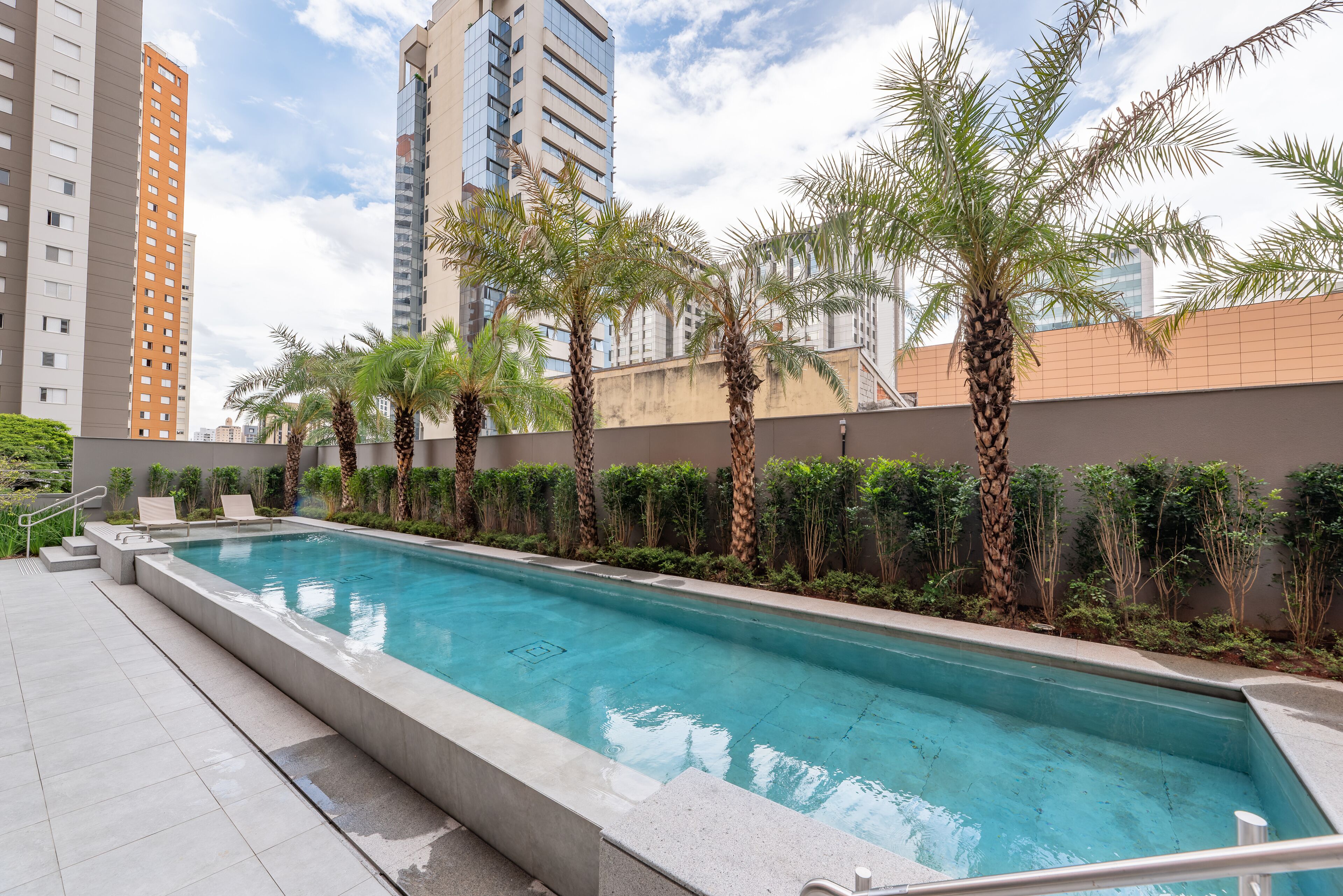A swimming pool with palm trees and a view of tall buildings.