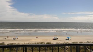 A beach view from a balcony with a railing, ocean, and a few beachgoers. - Oceanfront Corner Three Bedroom Unit - Crescent Sands L5 (North Myrtle Beach)