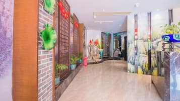 A hotel lobby with a brick wall, potted plants, and a marble reception desk.