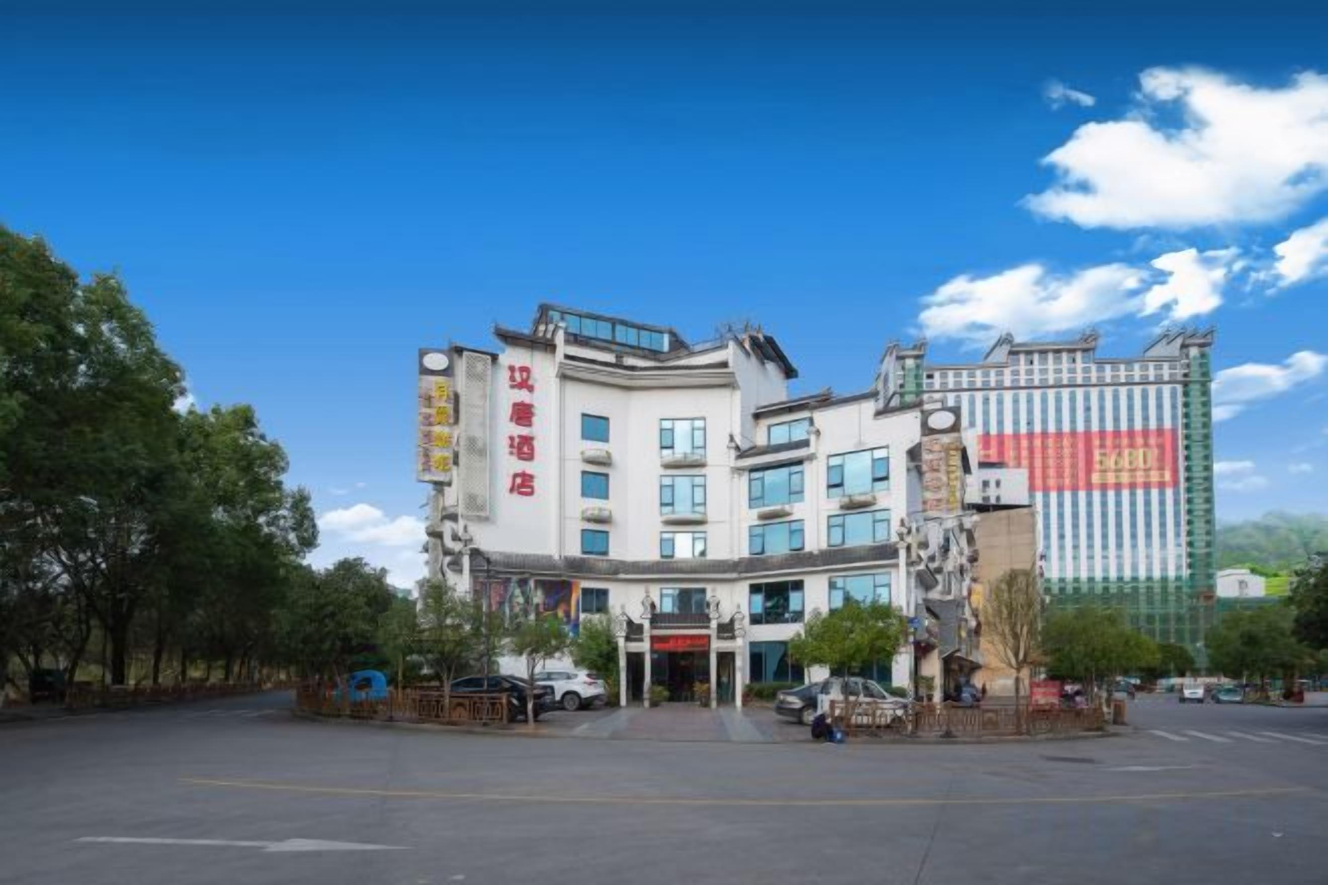 Ein mehrstöckiges Hotel im traditionellen Baustil, mit einem markanten Eingang und einer großen vertikalen Beschilderung an der Fassade.