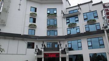 Un edificio blanco con numerosas ventanas y balcones adornados con plantas.