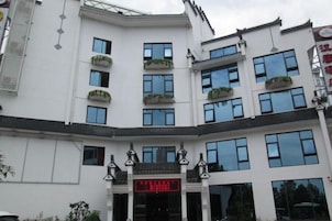 Un edificio blanco con numerosas ventanas y balcones adornados con plantas.