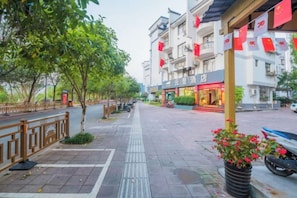 A street with a sidewalk, trees, and a building with a storefront.