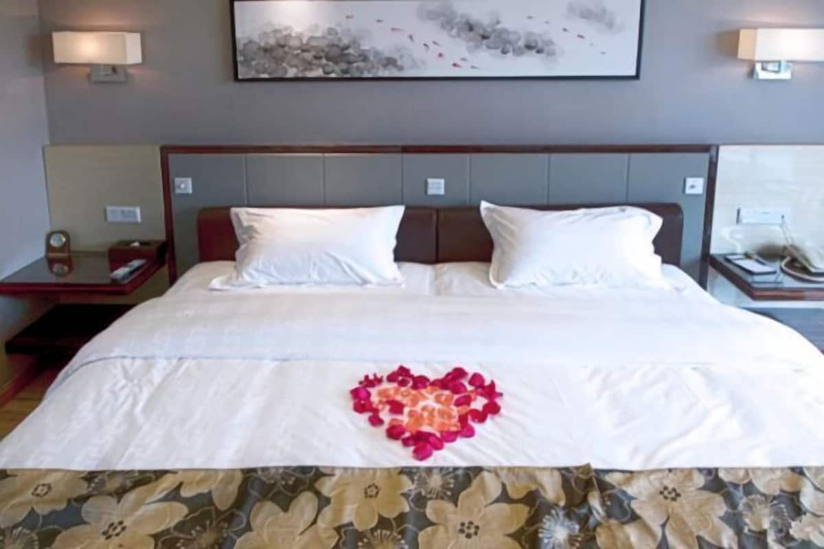 A hotel room with a large bed, two bedside tables, and a wall-mounted artwork.