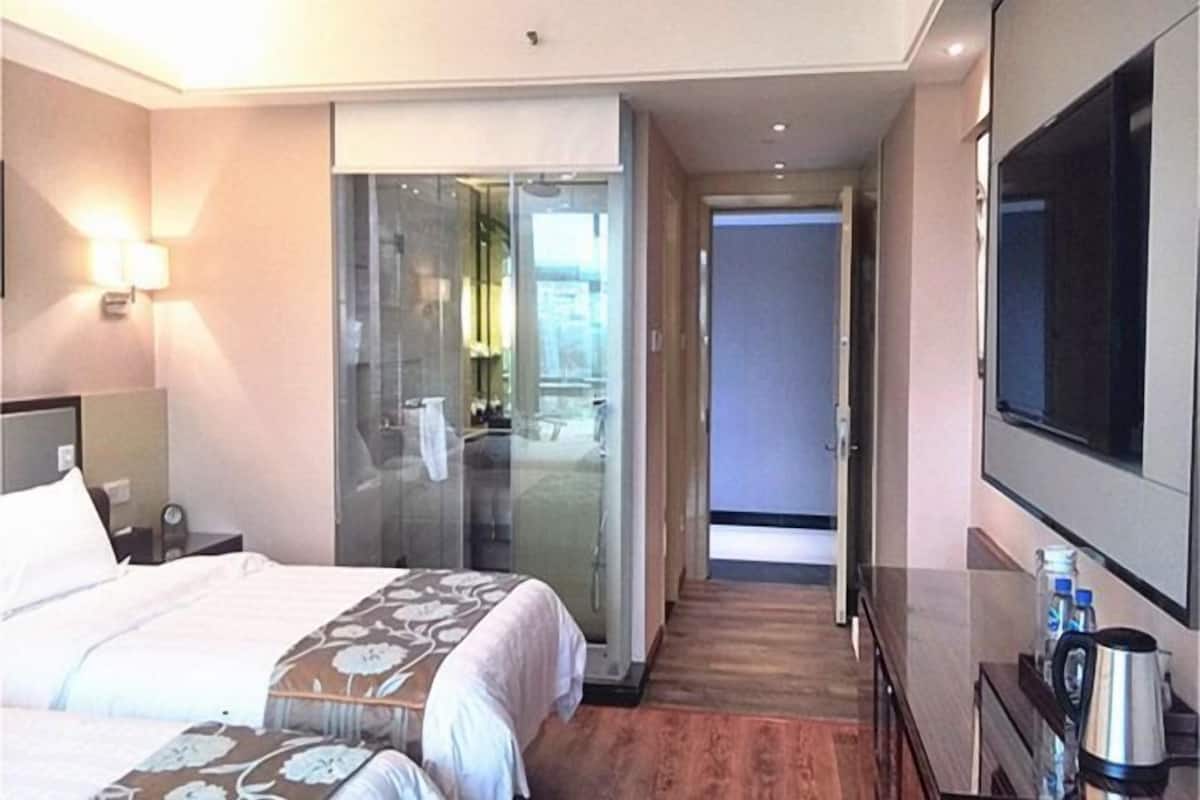 A hotel room with a bed, a desk, a TV, and a sliding door leading to a bathroom.