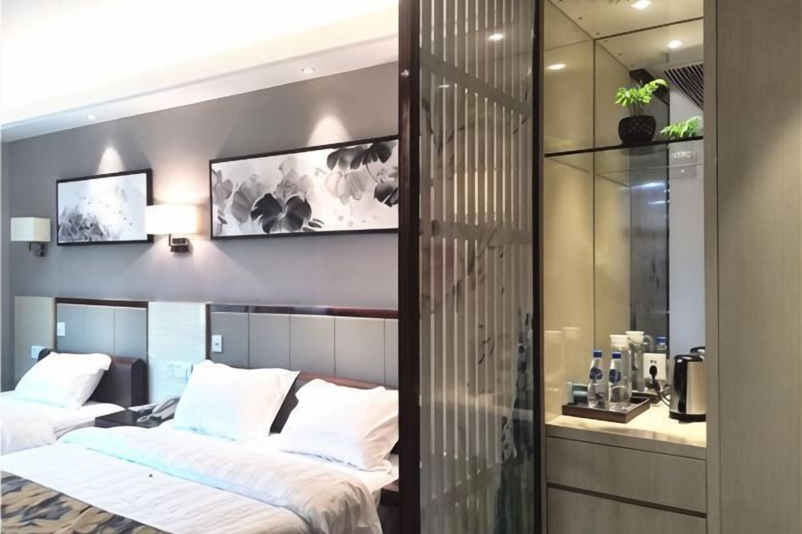 Una habitación de hotel moderna con una cama grande, mesitas de noche, un espejo y obras de arte en las paredes.