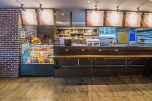 A bar area with a refrigerated display case, shelves with bottles, and a counter with a menu board. - Hantang Hotel (Taining)