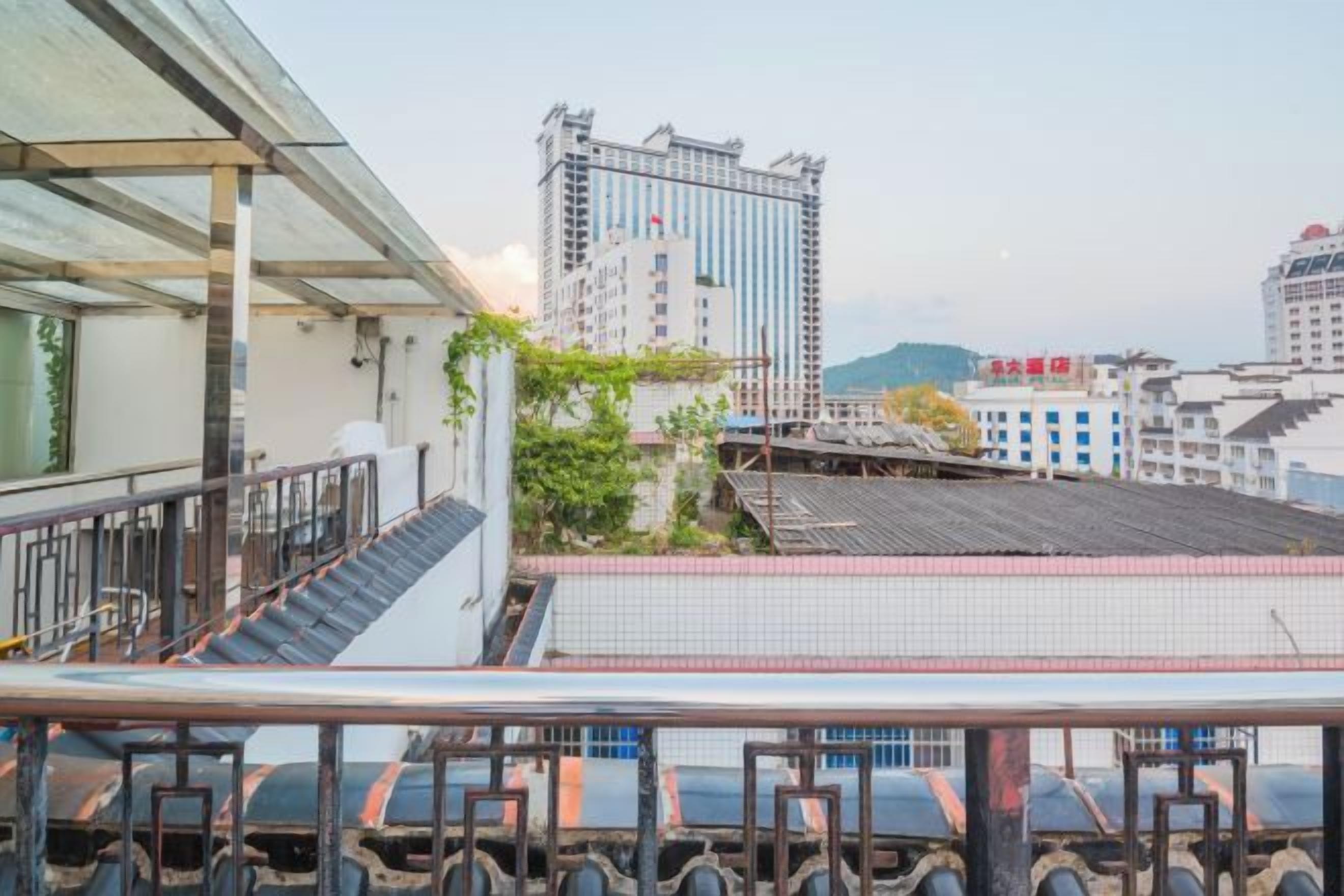 A high-rise building with a modern design, a rooftop garden, and a view of the cityscape.