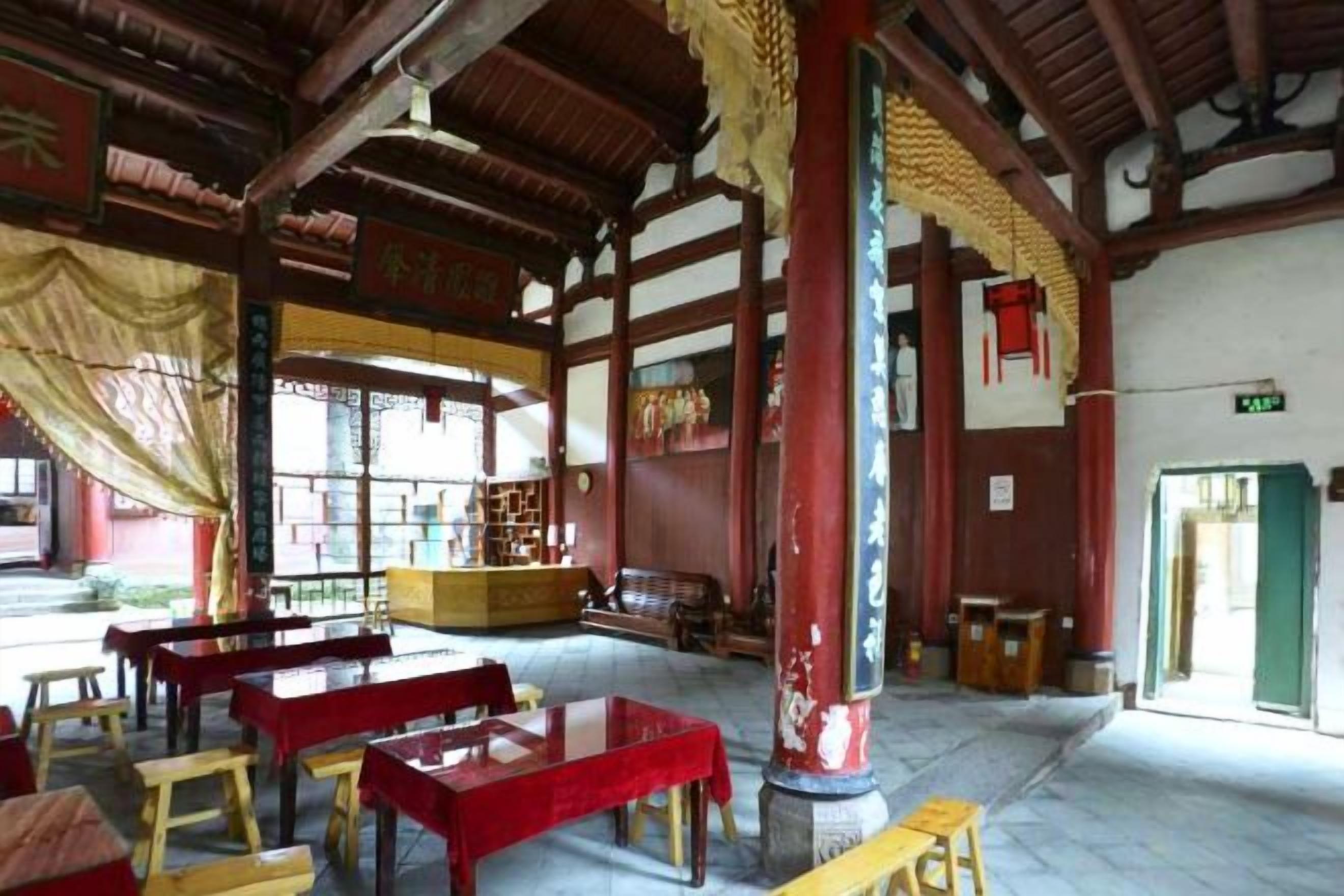 Un interior con vigas de madera tradicionales, muebles rojos y amarillos, y un pilar central.