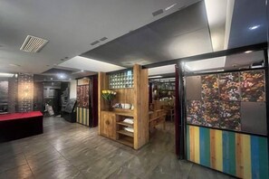 Un vestíbulo de hotel con una mesa de recepción, una zona de estar con madera y una colorida exhibición en la pared.