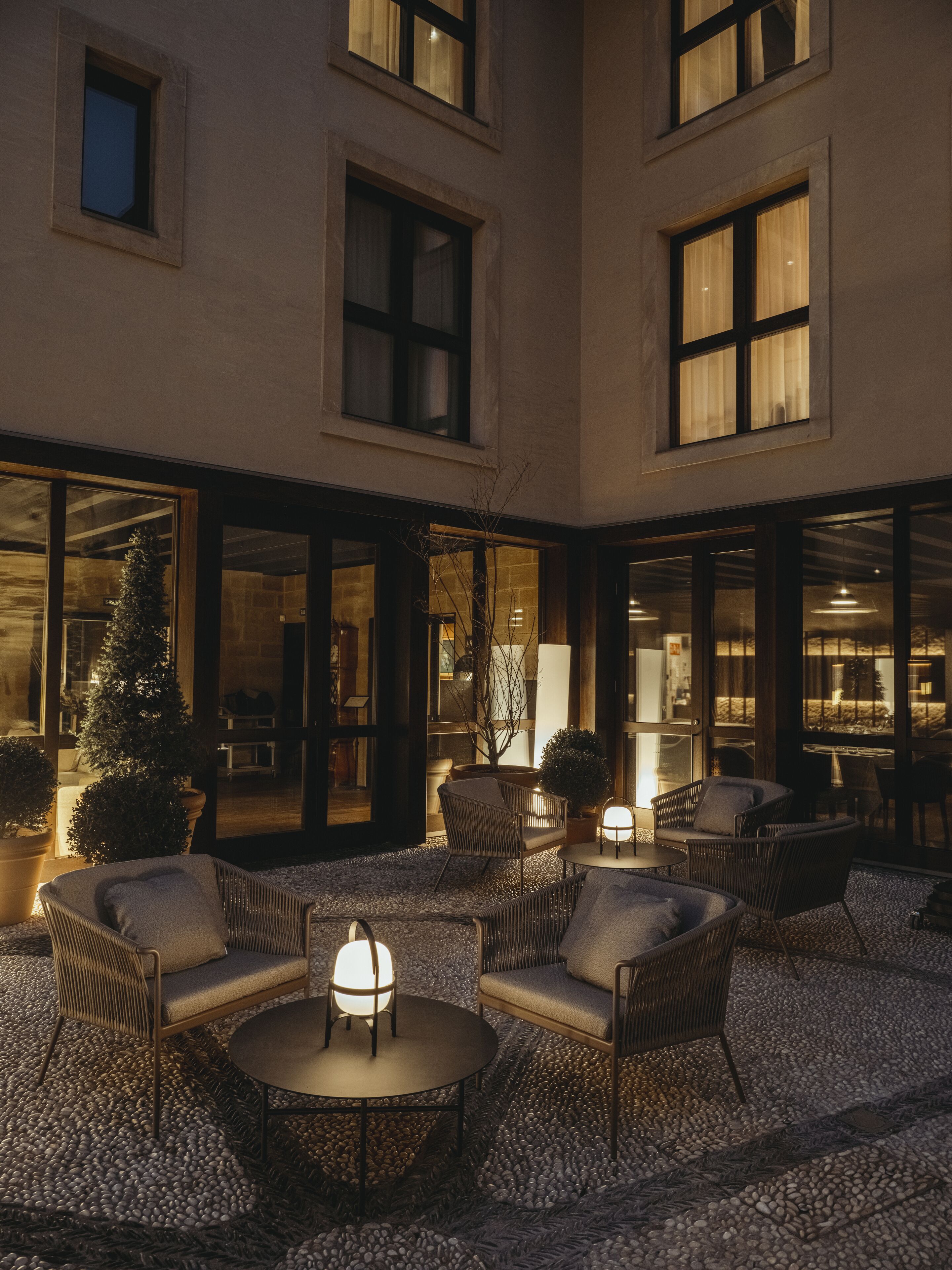 A courtyard with outdoor seating, a Christmas tree, and a well-lit interior visible through the windows.