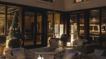A courtyard with outdoor seating, a Christmas tree, and a well-lit interior visible through the windows.