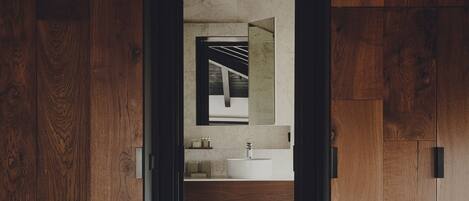 Interior de madera con baño que incluye lavamanos, espejo y toallero.