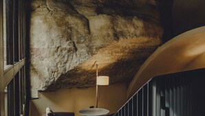 Un interior moderno con una pared de piedra, una mesa redonda y una escalera.