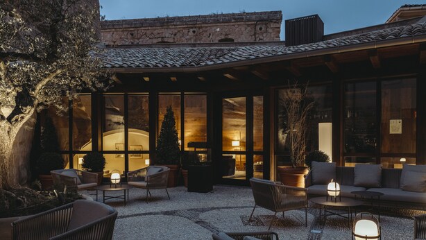 Un patio al aire libre con mobiliario de mimbre, un árbol de Navidad y una pared de piedra.