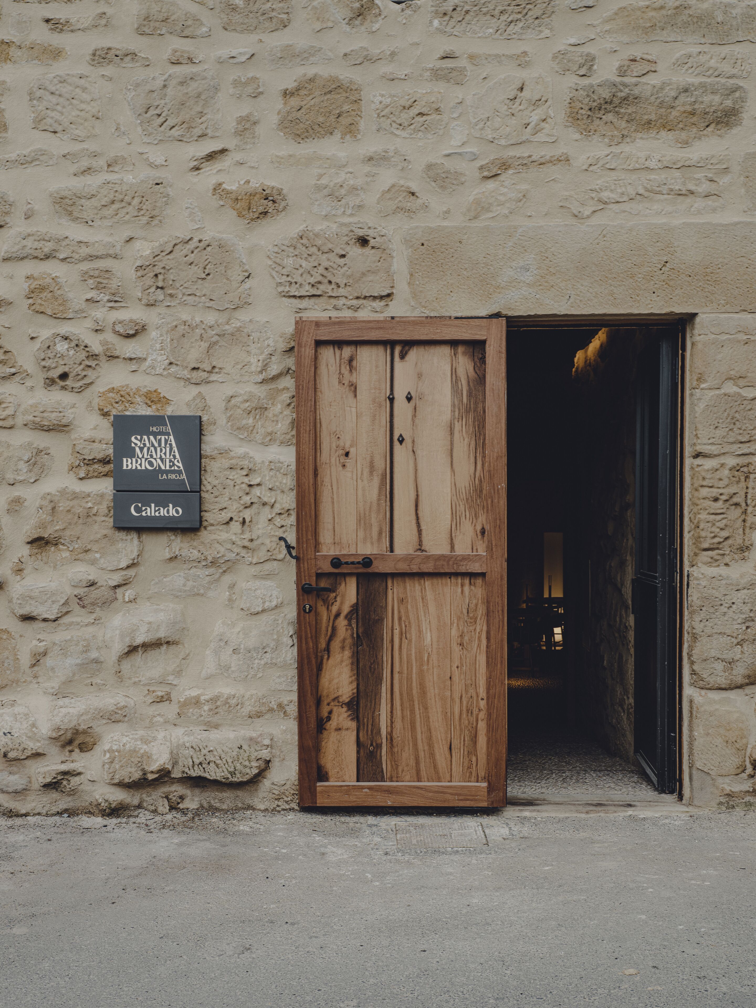 Una puerta de madera rústica con un letrero que dice 'Hotel Santa Maria Briones La Rioja Calado'.