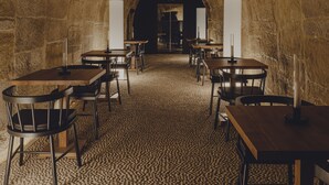 Habitación con paredes de piedra, mesas y sillas dispuestas para comer.