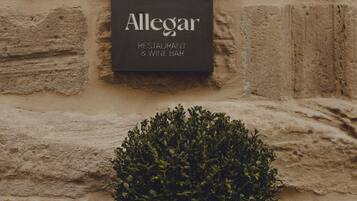 Schild mit der Aufschrift 'Hotel Santa Maria Briones' und 'Allegar Restaurant & Wine Bar' an einer Steinmauer.