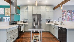 Une cuisine moderne dotée d’appareils électroménagers en acier inoxydable, de meubles de couleur gris clair et d’un îlot central.