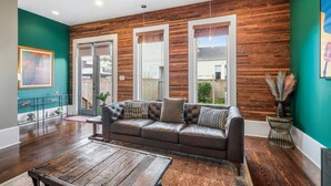 Un salon moderne avec un canapé en cuir, un plancher en bois et une grande fenêtre équipée de stores.