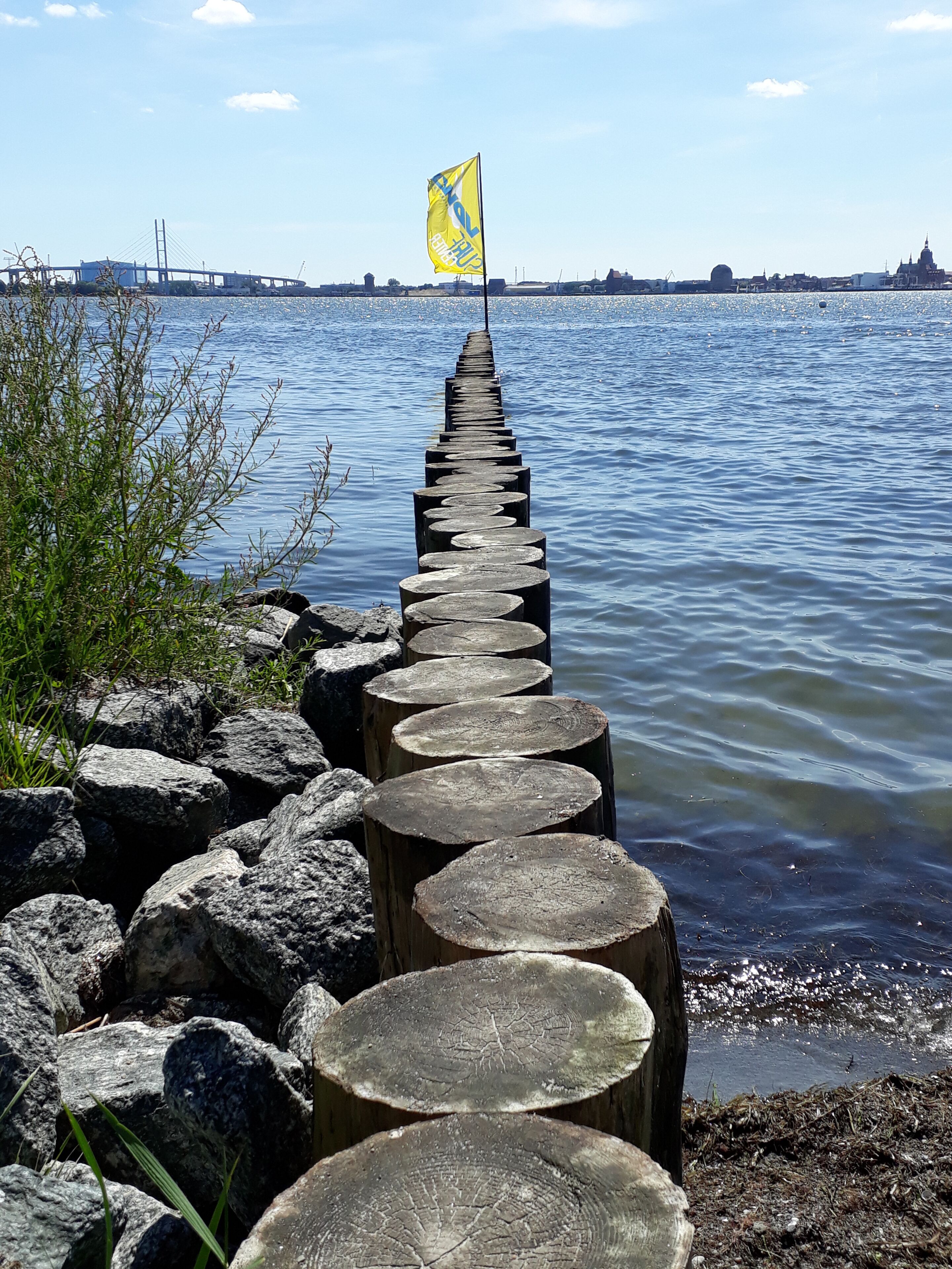 Une jetée en bois s’étendant dans une étendue d’eau, avec un drapeau au bout.