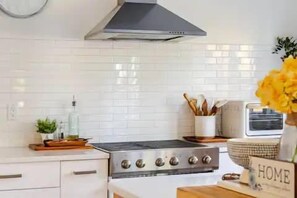 Een keuken met witte tegels, een roestvrijstalen fornuis en een moderne afzuigkap.