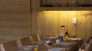 A wooden dining table set with plates, cutlery, and a fruit bowl, with a bottle of orange juice and a pitcher on the table. - Casa del Roble Avandaro (Valle de Bravo)