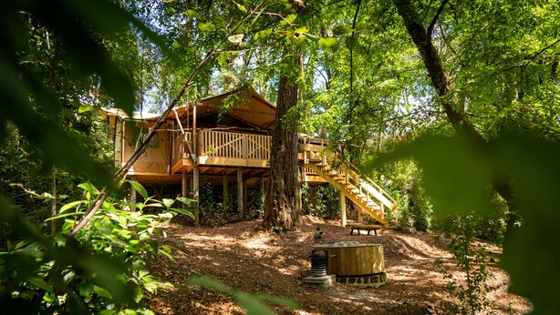 A wooden cabin with a deck and staircase, surrounded by trees and a hot tub. - Casa del Roble Avandaro (Valle de Bravo)