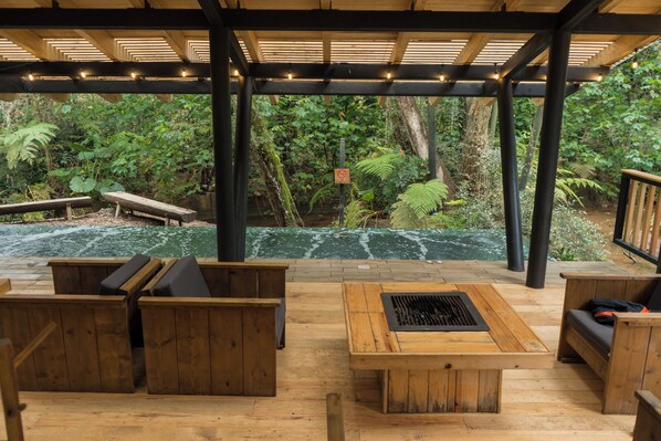 A covered outdoor seating area with wooden furniture and a view of a natural landscape. - Casa del Roble Avandaro (Valle de Bravo)