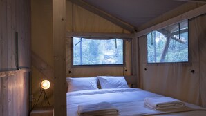 A wooden cabin room with a bed, two windows, a bedside lamp, and a view of trees. - Casa del Roble Avandaro (Valle de Bravo)