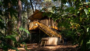 A wooden treehouse with a wooden staircase and a small deck.