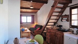 Une cuisine chaleureuse avec des poutres en bois, une table à manger avec des chaises, un canapé et une machine à café.