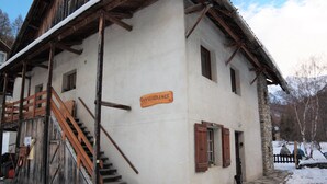 Un bâtiment rustique avec un escalier en bois et une enseigne sur laquelle on peut lire « PERSÉVÉRANCE ».