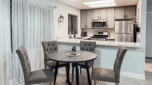 A modern kitchen with a central island, stainless steel appliances, and a dining area with four chairs. - Entire beautiful 2 bedroom house (North Highlands)
