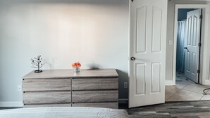 A bedroom with a wooden dresser, a bed, and a door leading to a hallway. - Entire beautiful 2 bedroom house (North Highlands)