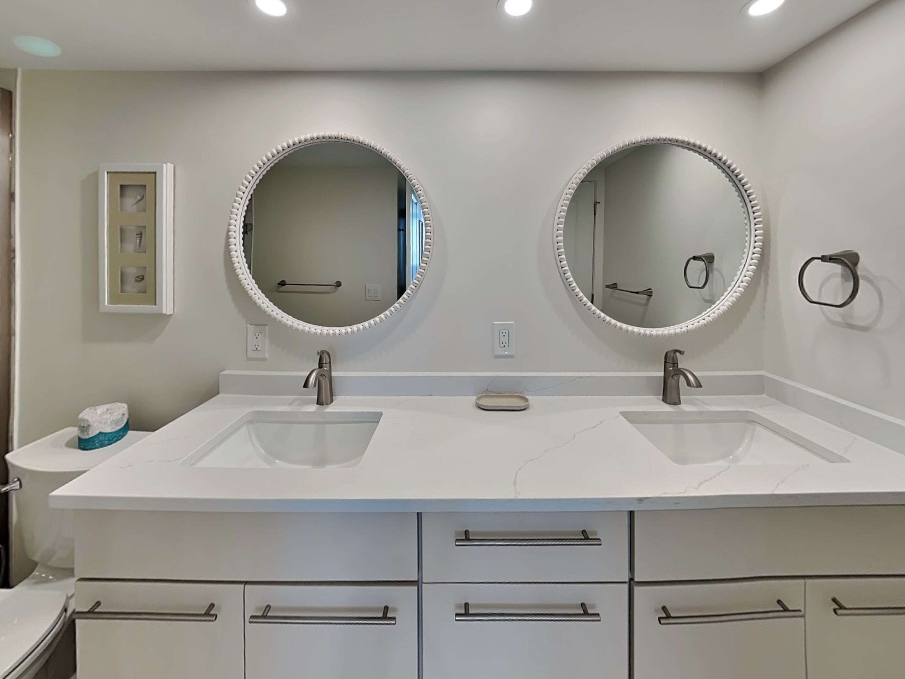Une salle de bain avec deux lavabos, un miroir au-dessus de chacun, et un porte-serviettes fixé au mur.