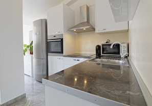 Una cucina moderna con elettrodomestici in acciaio inossidabile, un piano di lavoro in marmo e mobili bianchi.